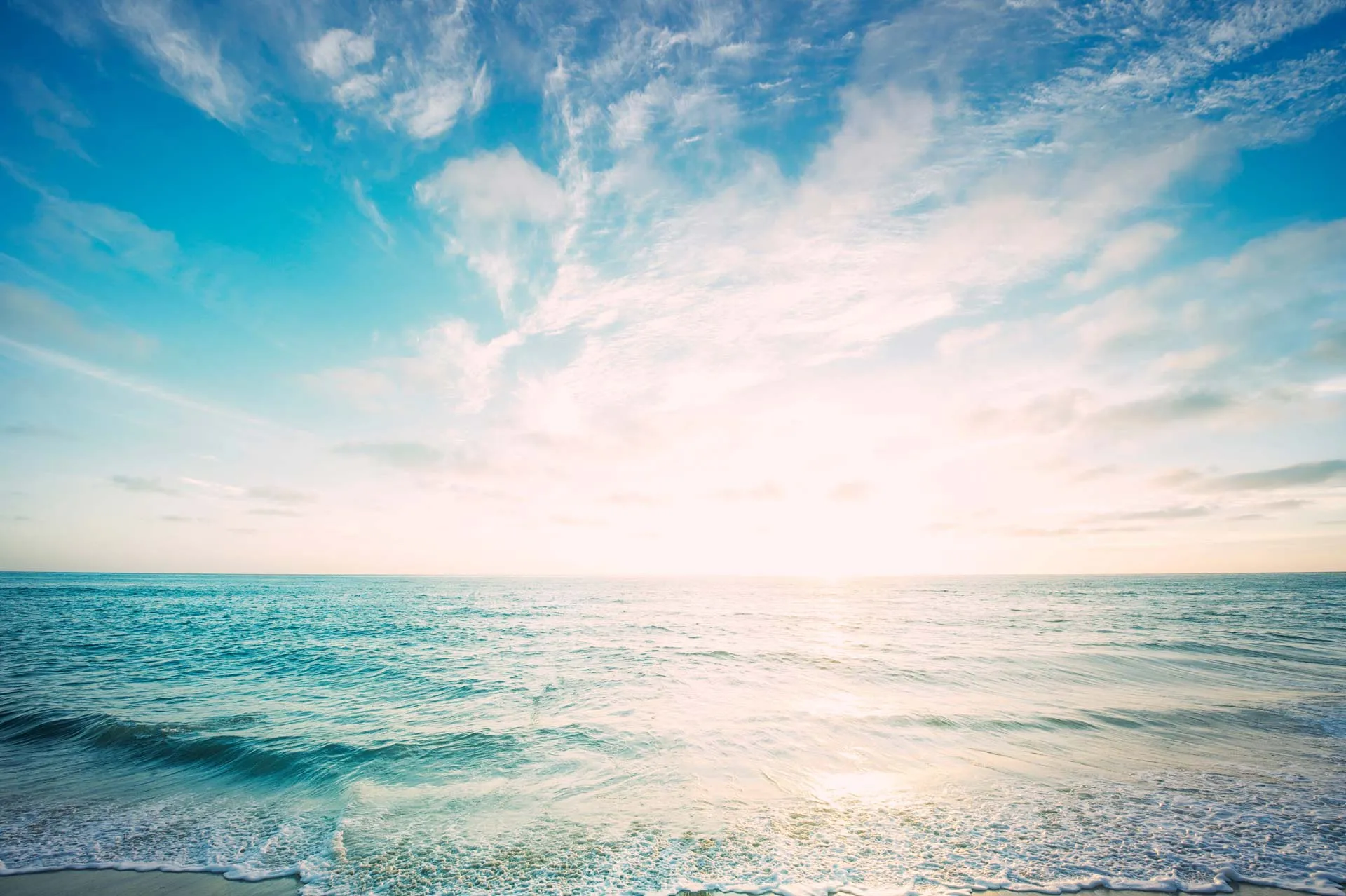Ruhiges Meer unter blauem Himmel mit Sonne und Wolken
